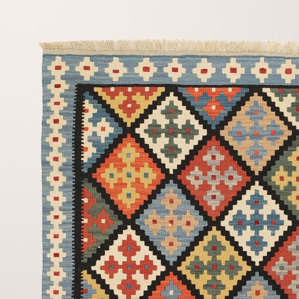 Ecke des Kelims mit blauer Bordüre, cremefarbenen Rauten und schwarzem Rautengitter